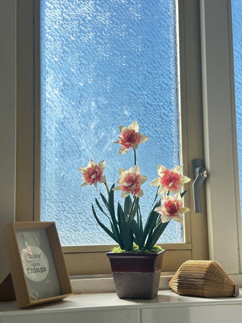 Dos flores de narciso realistas de papel crepé en una maceta de cerámica.