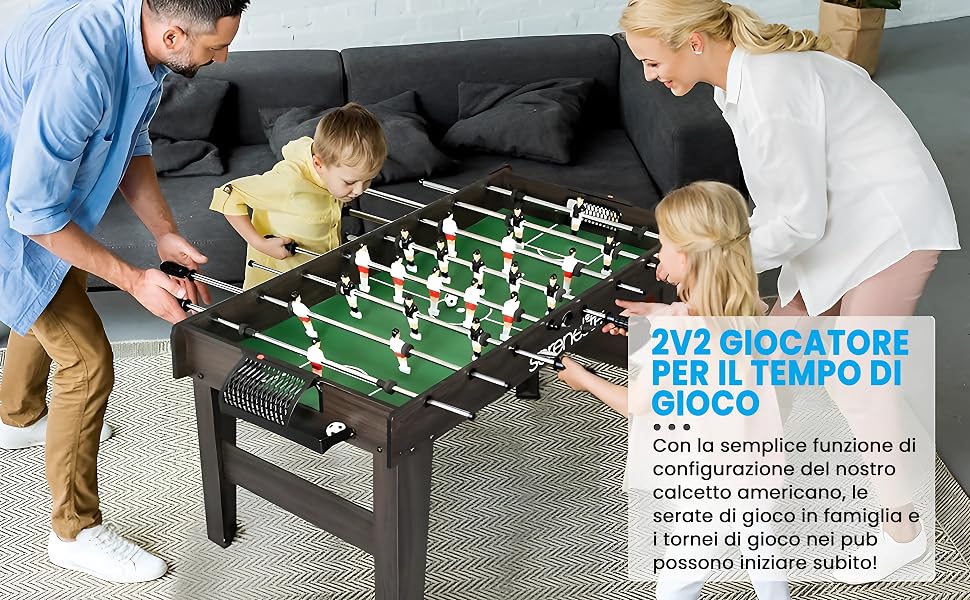 Famiglia che gioca a biliardino da tavolo. Adulti e bambini si sono riuniti attorno a una partita di calcio compatta sul tavolino da caffè in