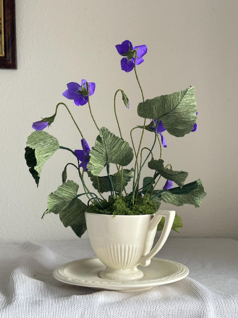 Flores realistas de papel crepé en una tetera antigua.