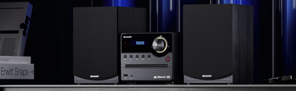 L'impianto Hi-Fi XL-B517D (BK) si trova su uno scaffale con libri e luce blu sullo sfondo. 