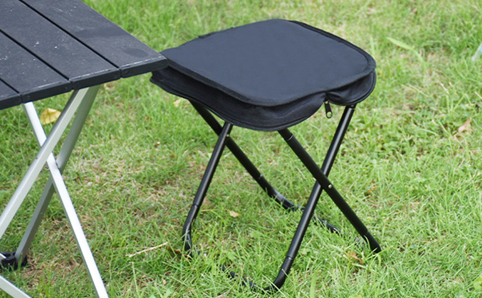Sgabello pieghevole nero o sedile portatile con struttura in metallo visualizzata sulla superficie erbosa.