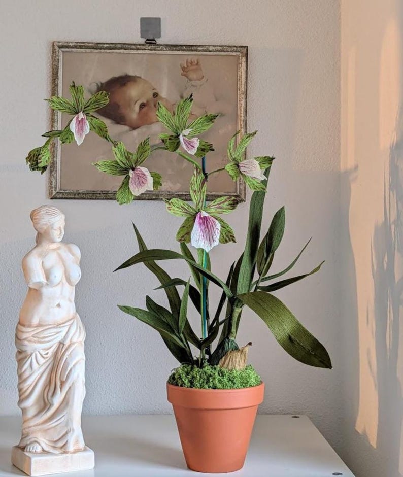 Flores de orquídea realistas de papel crepé en una maceta de terracota.