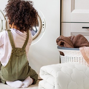 una bambina seduta sul pavimento davanti a una lavatrice.