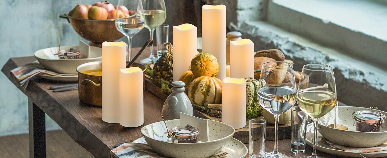 Elegante set da tavola con pi霉 candele a colonna bianche, bicchieri da vino e zucche decorative disposte su una superficie scura