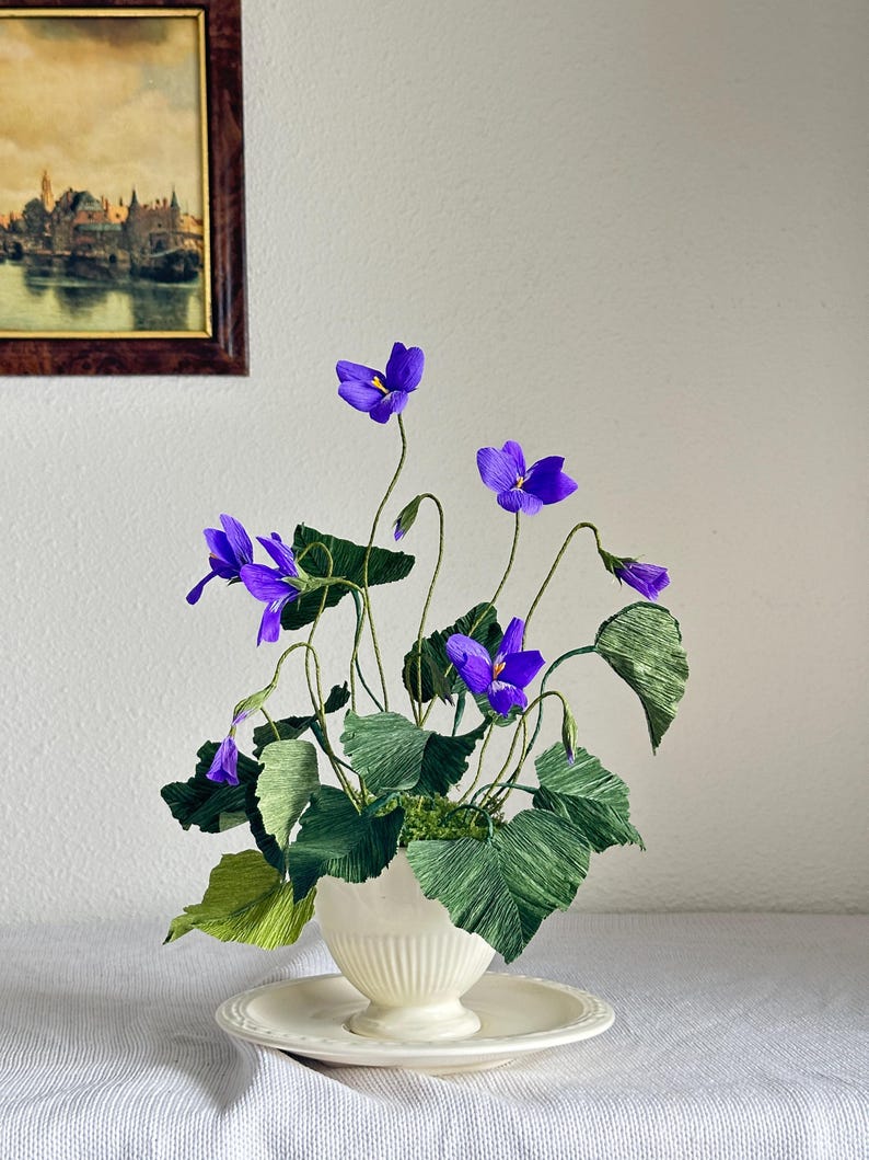 Flores realistas de papel crepé en una tetera antigua.
