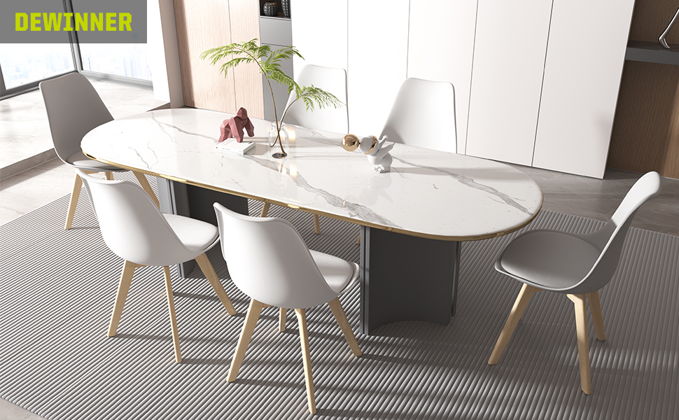 Set da pranzo moderno con tavolo ovale effetto marmo, sei sedie bianche con gambe in legno e armadi bianchi sullo sfondo. Tappeto grigio