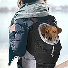 Una persona che indossa un cappotto invernale che trasporta un cane di piccola taglia in uno zaino da trasporto di colore scuro progettato per trasportare comodamente gli animali domestici