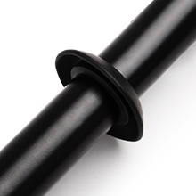 Primo piano di un oggetto cilindrico nero con una flangia o un disco circolare al centro, possibilmente un componente o un connettore